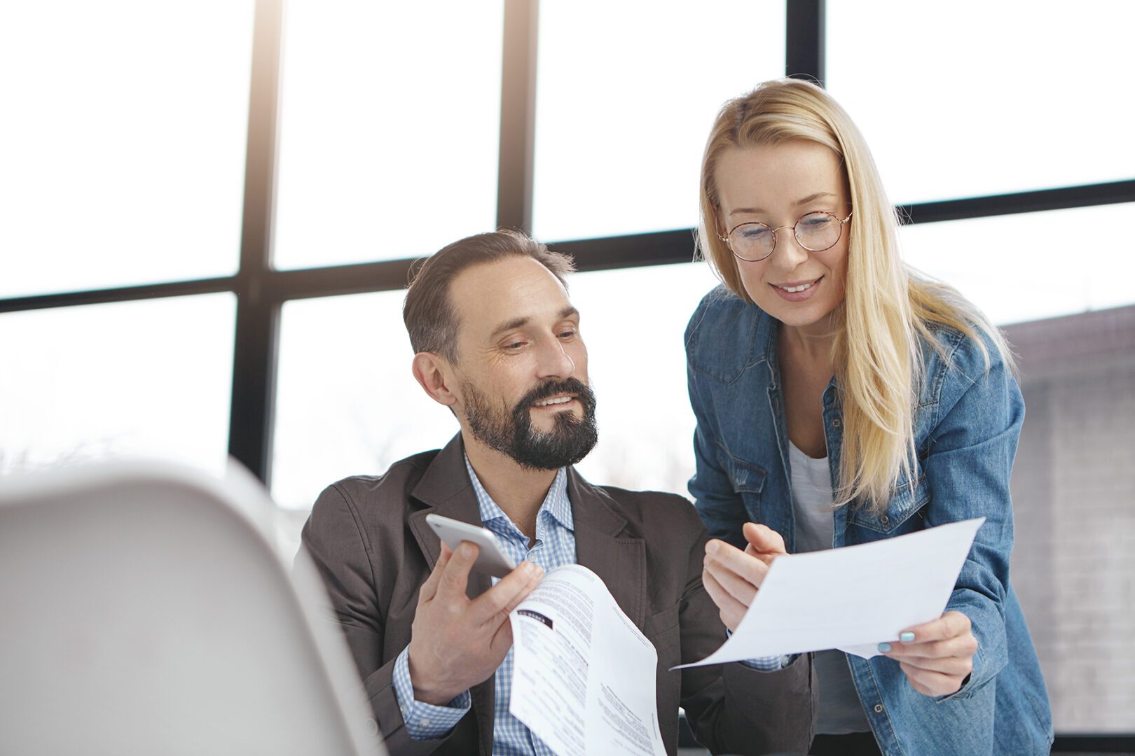 Two professionals reviewing documents in a modern office
