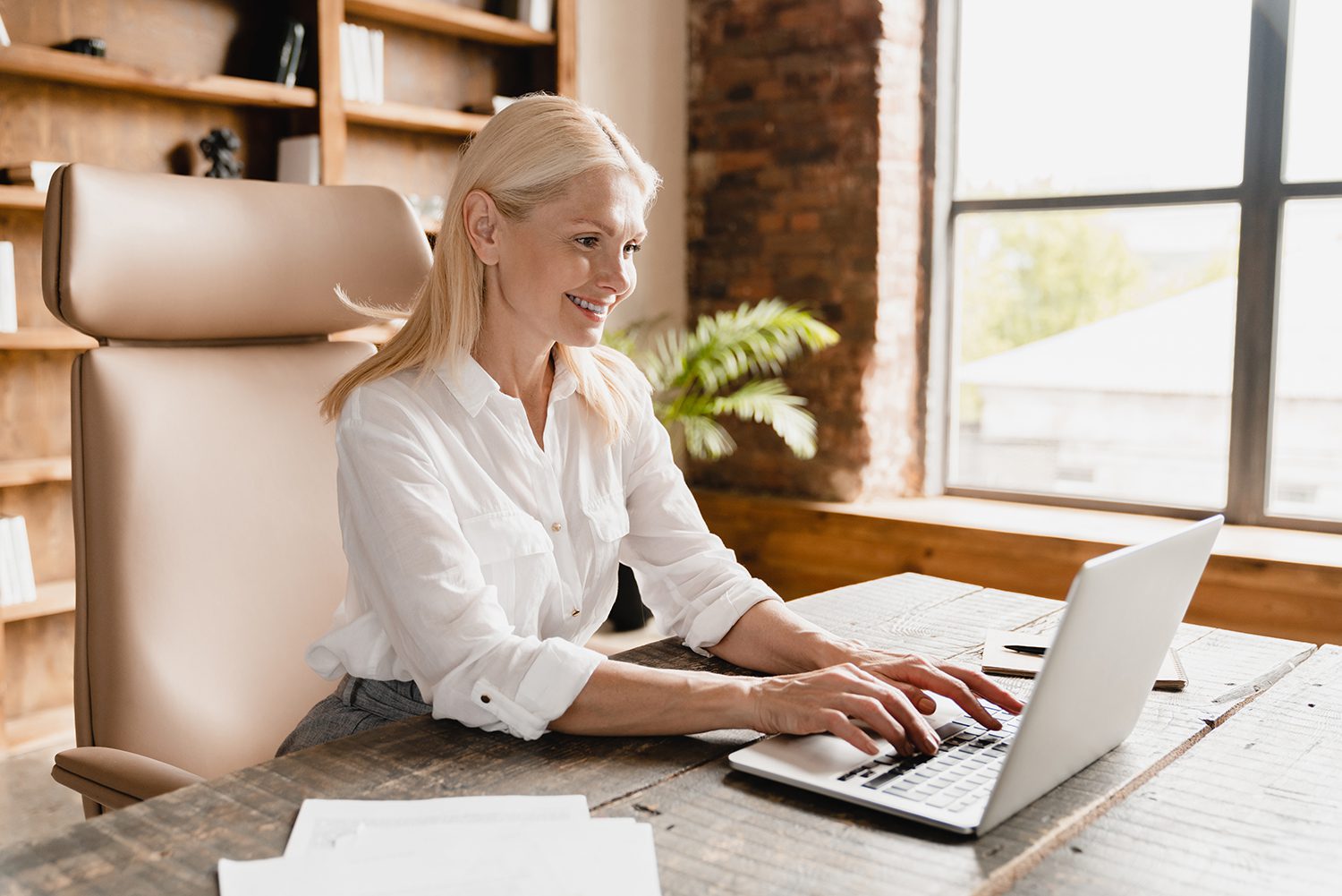 Boss working, typing on laptop computer searching information, social media watching webinars online Side view portrait of a confident smiling caucasian businesswoman boss working in office, typing on laptop computer, searching information web, social media, watching webinars online